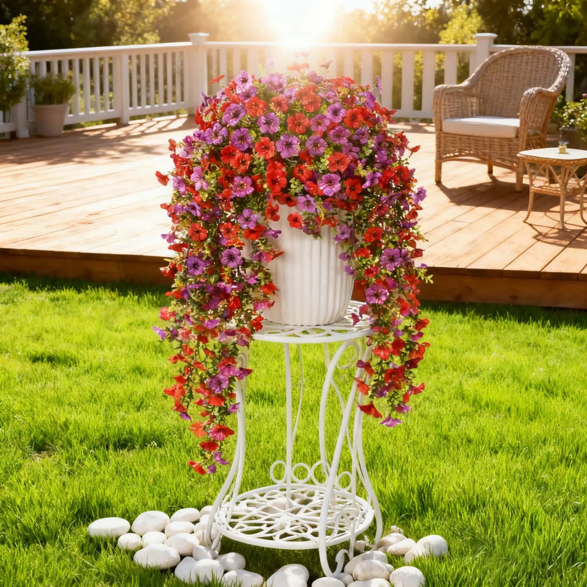 A white trellis display featuring vibrant faux silk flowers in shades of pink, red, and purple on a wooden deck.