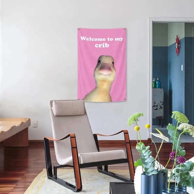 Pink wall tapestry featuring a cartoon duck saying Welcome to my crib above a modern chair.