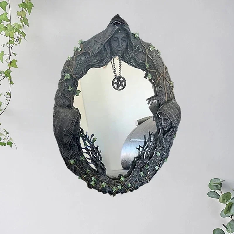 A dark, leafy wreath mirror frame featuring a face and a hanging pentagram amulet.