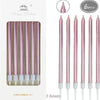 A set of six metallic pink birthday cake candles with holders displayed in a box.