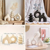A set of natural and black ceramic vases displayed on a wooden surface with sheer white fabric backdrop.