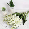A bouquet of artificial white delphinium flowers displayed on a white surface.
