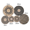 A collection of woven straw wall hangings in various sizes and patterns, including round mats with geometric designs.