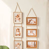 A vertical arrangement of five wooden photo frames with natural wood tones and white mats hanging on a light wall.