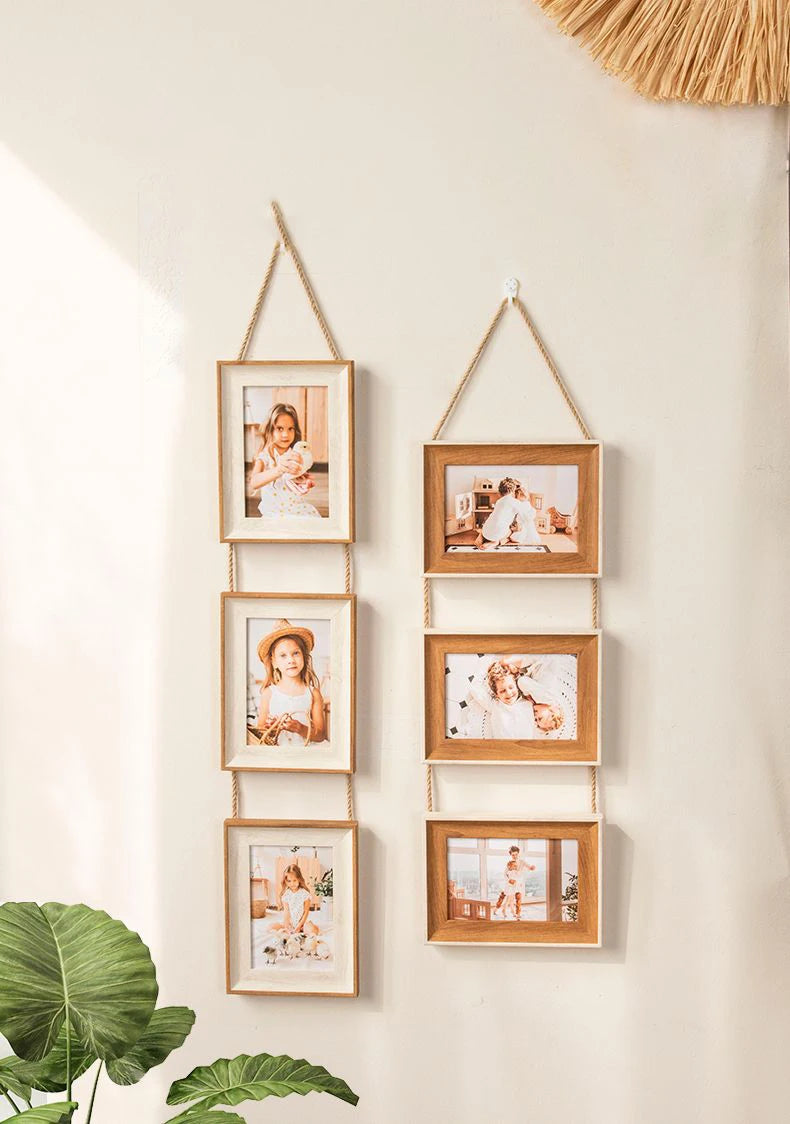 A vertical arrangement of five wooden photo frames with natural wood tones and white mats hanging on a light wall.