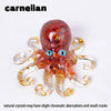 A translucent reddish-orange crystal octopus statue with blue eyes and gold inclusions.