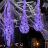 Halloween glowing spider web decoration featuring light-up eggs hanging in a dark setting
