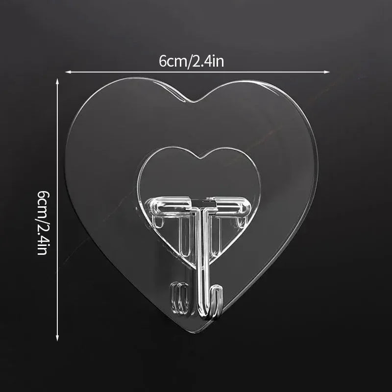 A clear heart-shaped silicone adhesive hook with a metal hanger attached, shown against a dark background.