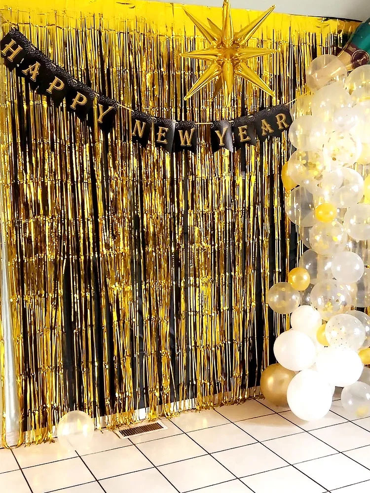 Golden metallic foil fringe curtains with a happy new year banner and gold star decoration for a party backdrop