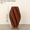 A terracotta-colored, textured wave vase with a narrow base and flared opening.
