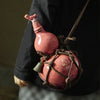 A traditional ceramic wine gourd with a narrow neck is suspended by twine, featuring an engraved mark.