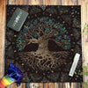 A dark brown velvet tablecloth featuring a gold-toned tree root design and foliage, set on a wooden surface.