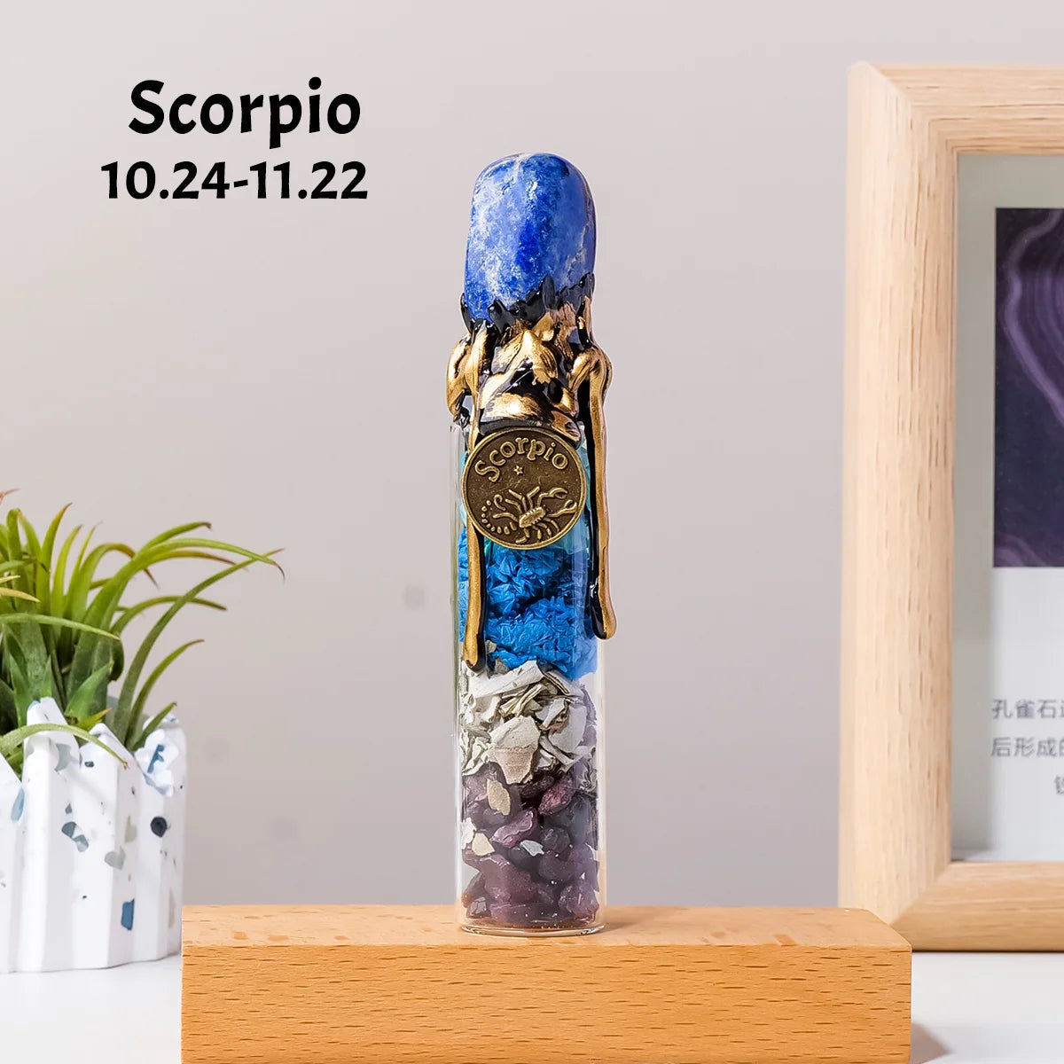 A blue crystal bottle shaped like a scorpion with raw healing stones, displayed on a wooden surface.