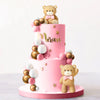 A pink tiered cake decorated with gold and white bear figures and spherical decorations.