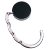 A silver foldable handbag hook with a round black plate, designed for hanging bags on tables and desks.