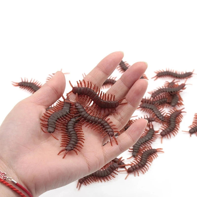 A hand holds a collection of realistic plastic bugs including cockroaches, centipedes, and scorpions.