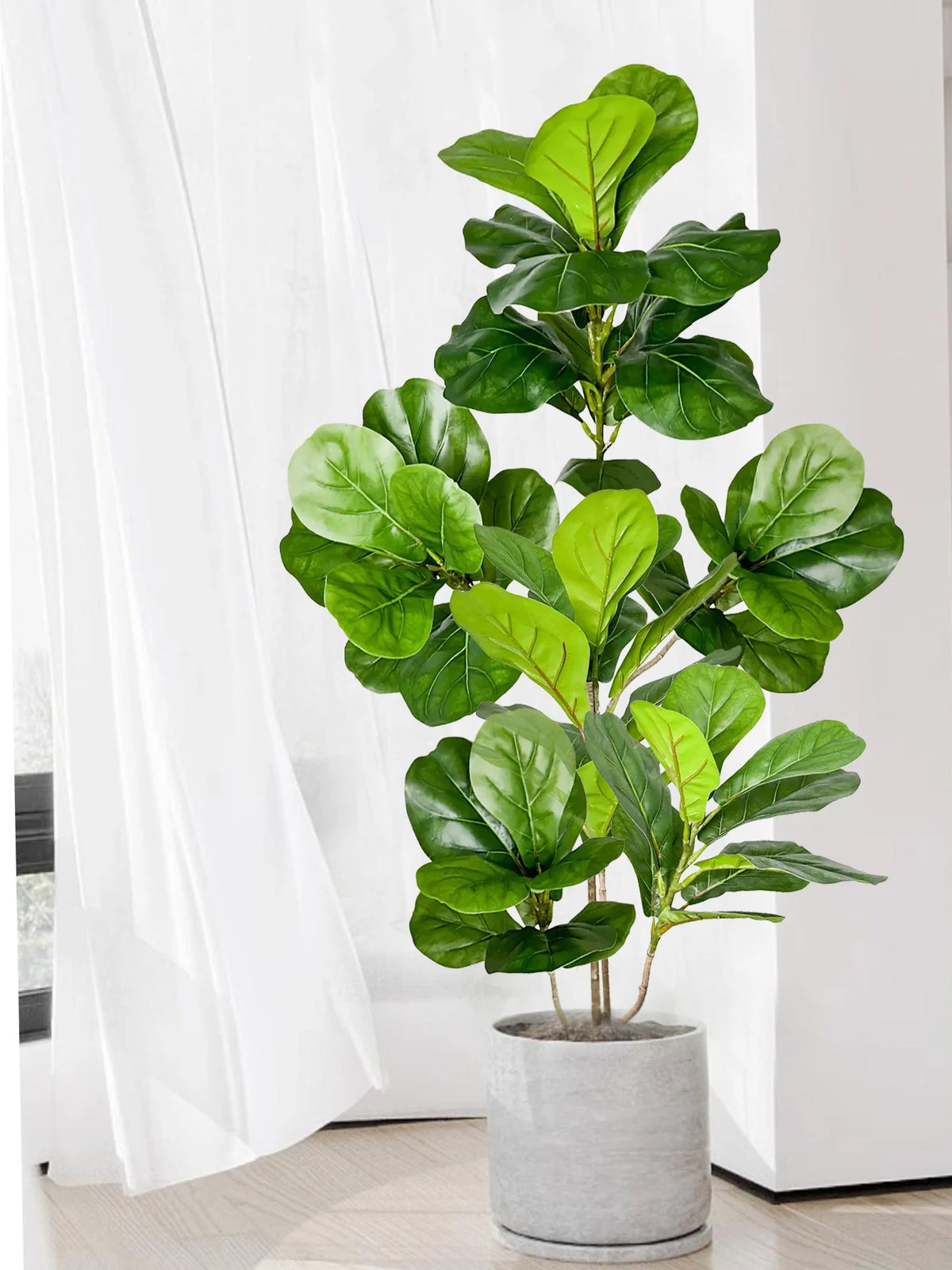 A large artificial ficus tree with vibrant green fiddle leaves potted in a gray cylindrical planter.