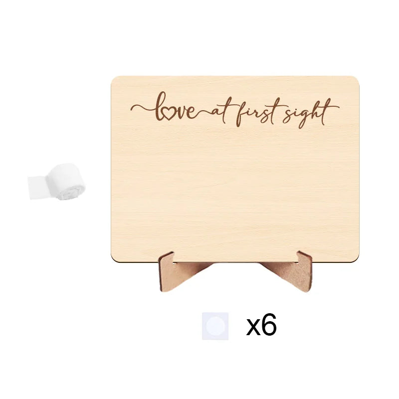 A light wood photo frame with cursive text that reads love at first sight, featuring a ribbon for a pregnancy announcement.