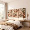 A bedroom scene featuring a wooden bed frame and a wall display of three floral canvas art prints with earthy tones.