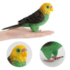 Hand-painted resin parrot figurine with yellow head and green body resting on a hand.