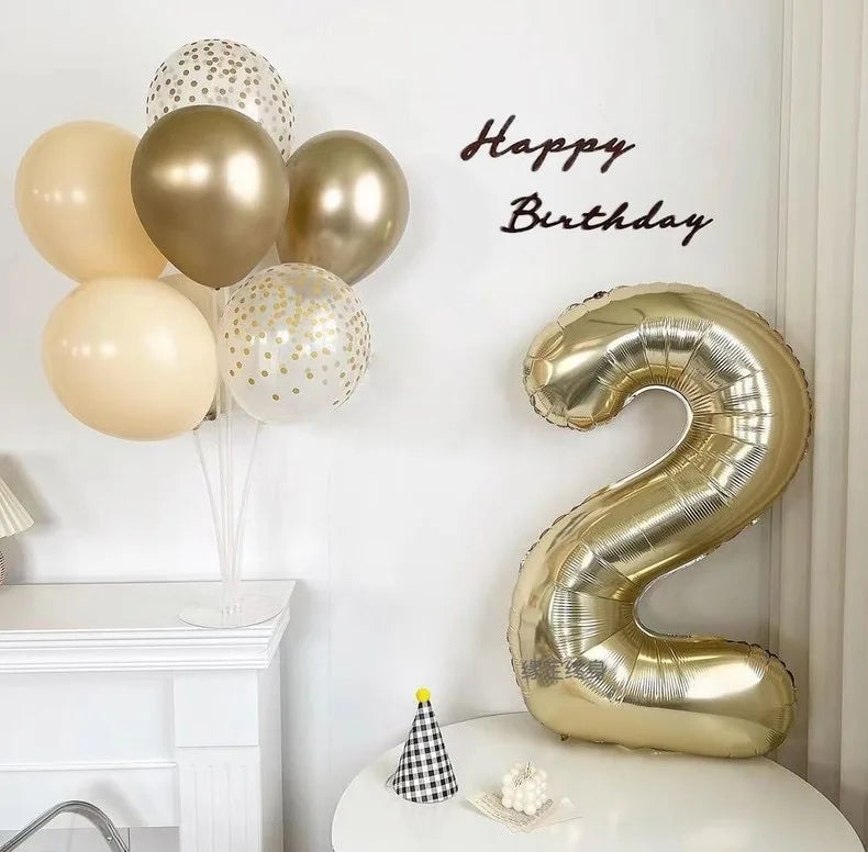 A large champagne gold foil number balloon shaped like the number 2 is displayed on a white table.