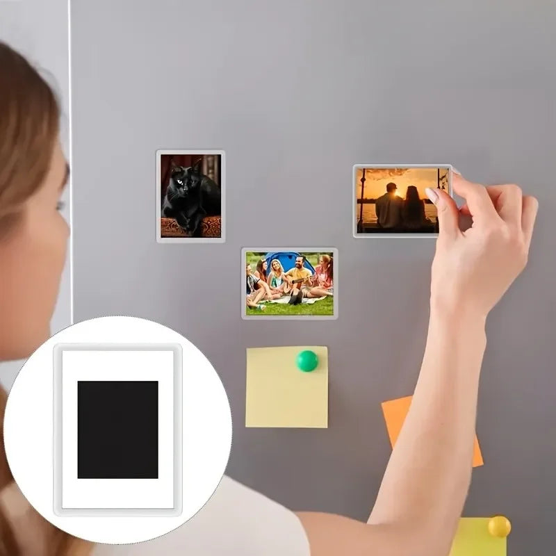 A hand is placing square photo frame magnets onto a gray wall, with an example of a black cat and a sunset visible.