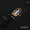 A golden wooden pendant featuring a depiction of Our Lady of Grace, suspended by a dark cord and tassel.