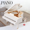 A white piano-style music box is shown open, revealing a golden mechanism and a small ballerina figure.