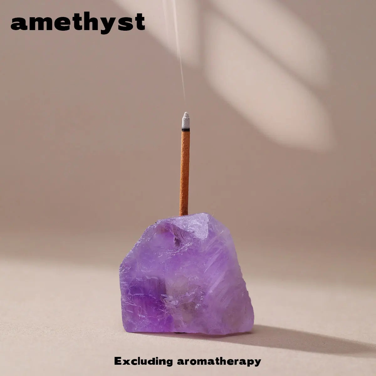 A purple amethyst crystal sits on a surface with a wooden stick and a small metal tip, used as an aromatherapy holder.