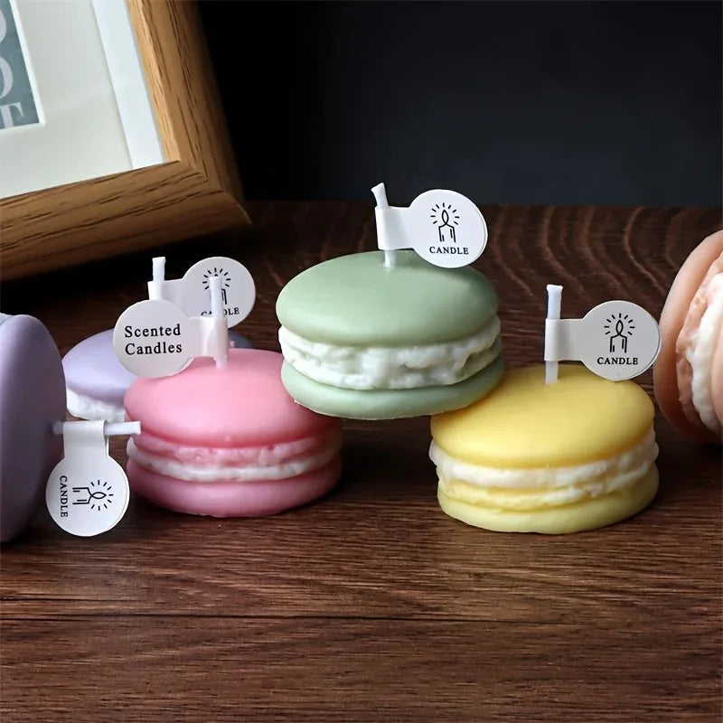 A display of colorful macaron-shaped soy wax candles in pink, green, and yellow on a wooden surface.