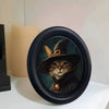 A round black photo frame featuring a dark portrait of a cat wearing a wide-brimmed hat.