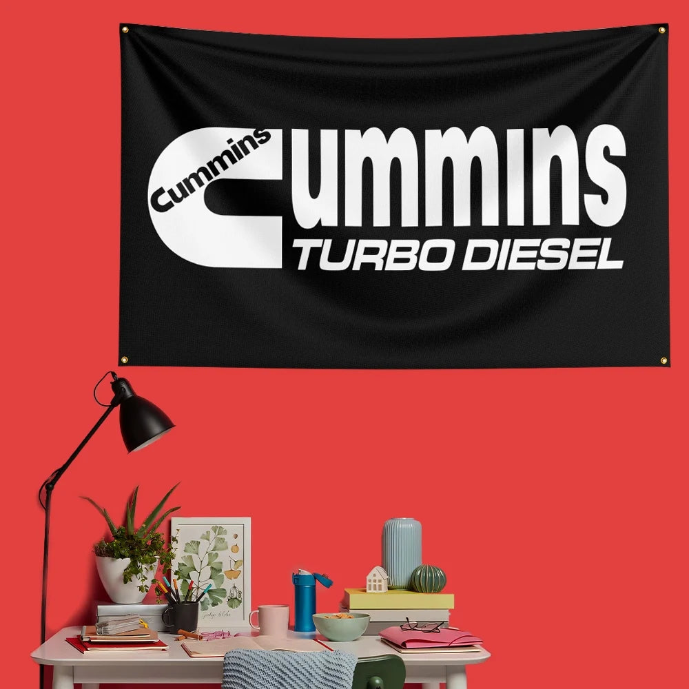 A black flag banner with white text reading Cummins Turbo Diesel mounted on a red wall.
