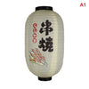 A light beige paper hanging lantern with black Japanese calligraphy and illustrations of skewers.
