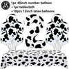 A set of cow print number balloons and a tablecloth for a farm-themed party decoration.