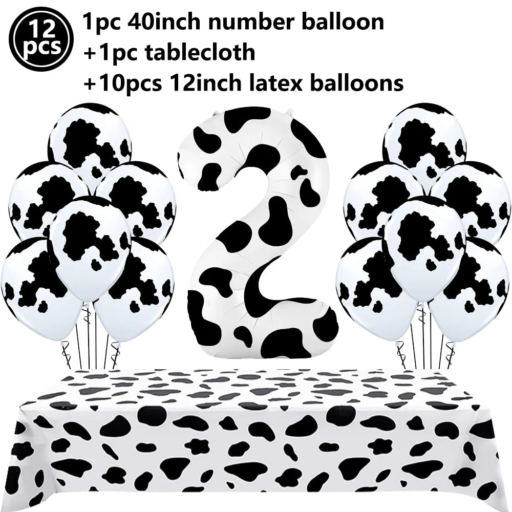 A set of cow print number balloons and a tablecloth for a farm-themed party decoration.