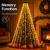 A Christmas tree decorated with warm white lights and red ornaments, displayed in a living room setting.