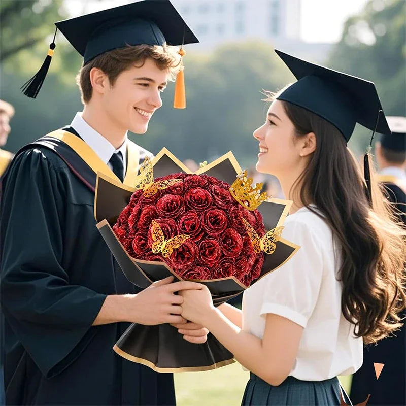 A smiling graduate in a black gown and cap is handing a bouquet of red glitter artificial roses to a female student.