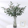 Artificial olive branch with dark green leaves and small reddish-brown fruits displayed in a clear glass vase.