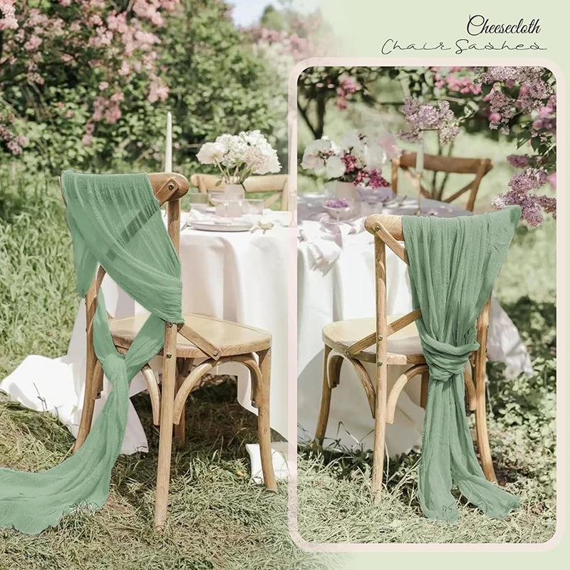 A rustic outdoor wedding setting featuring sage green gauze chair sashes and a white table runner.