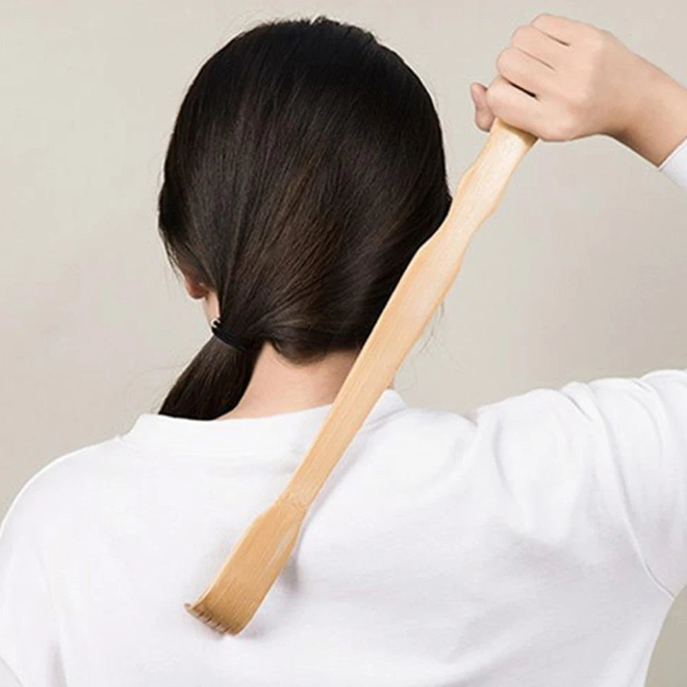 A person is using a bamboo back scratcher with a roller massager on their back.