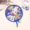 A round blue fabric fan with a floral pattern is shown on a light background.