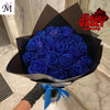 A bouquet of deep blue artificial roses wrapped in black paper with a blue ribbon.