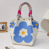 A light blue and white floral jacquard knitted shoulder bag with multicolored braided strap.