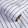 Roll of self-adhesive 3D wood grain wall panels with black and white stripes on a marble background