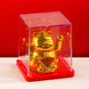 A golden waving lucky cat figurine inside a clear red display box on a white surface.