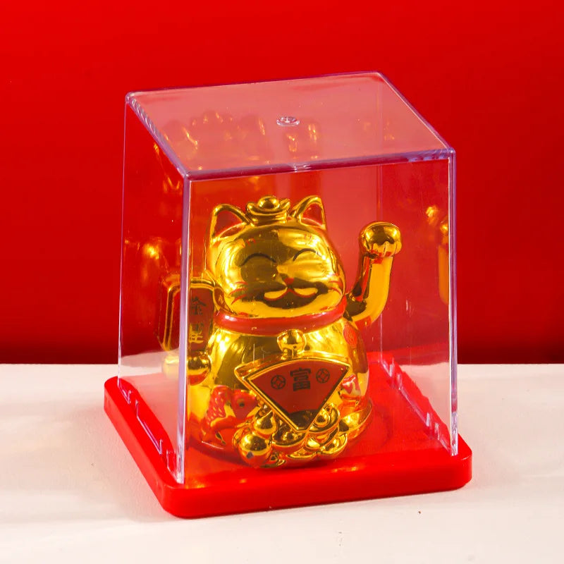 A golden waving lucky cat figurine inside a clear red display box on a white surface.