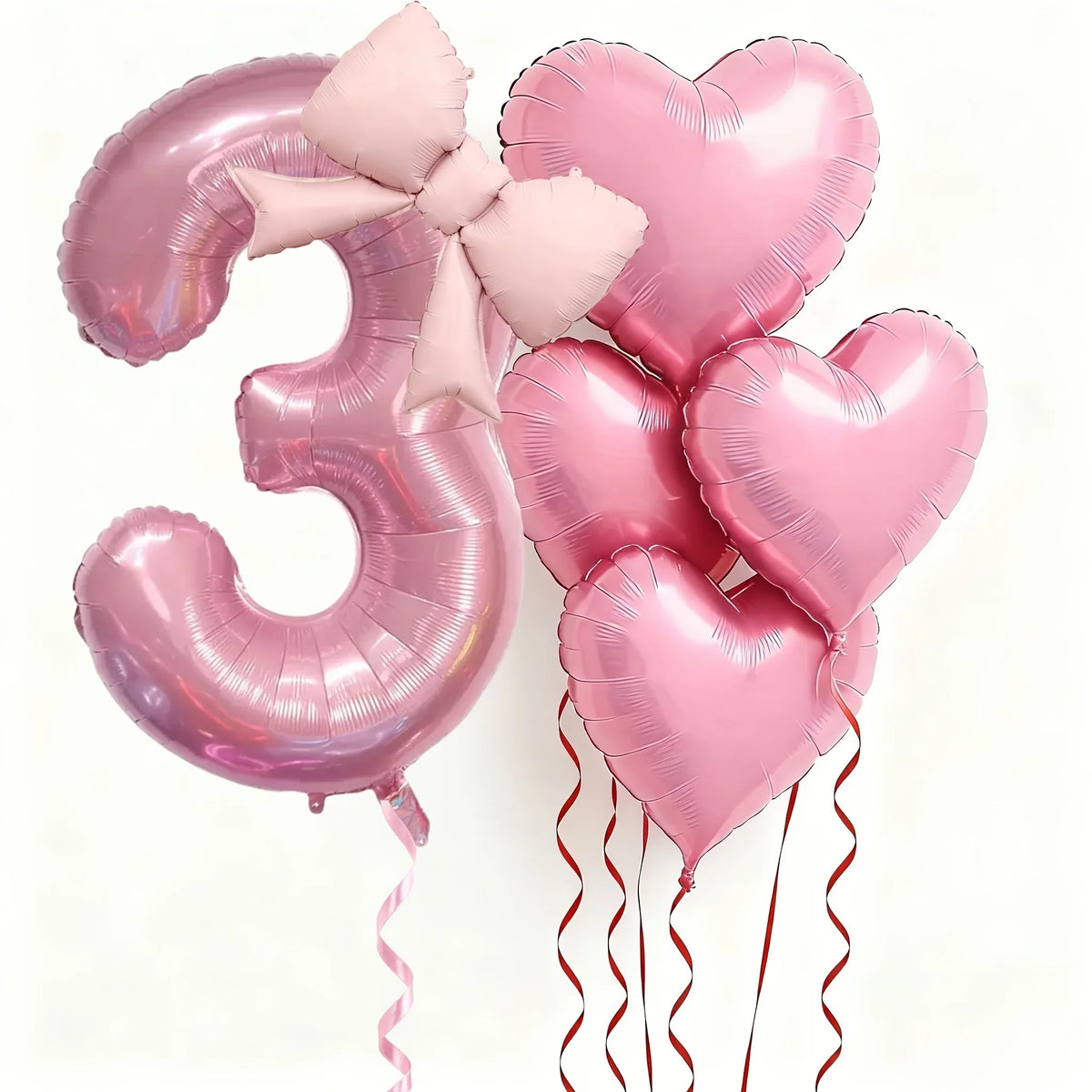 Pink foil balloons shaped like the number three and hearts for party decoration
