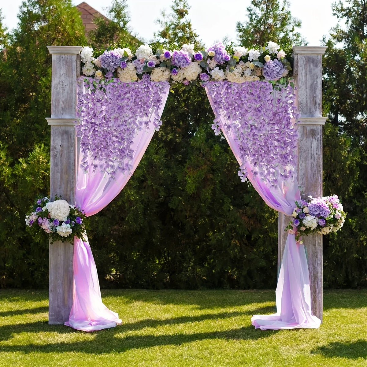 An archway decorated with purple and white flowers and draped sheer purple fabric in an outdoor setting.