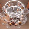 A cluster of large clear bubble balloons in various shades of gold, silver, and bronze suspended from the ceiling.