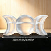 A clear natural selenite triple moon charging bowl with a rounded, crescent shape resting on a dark surface.